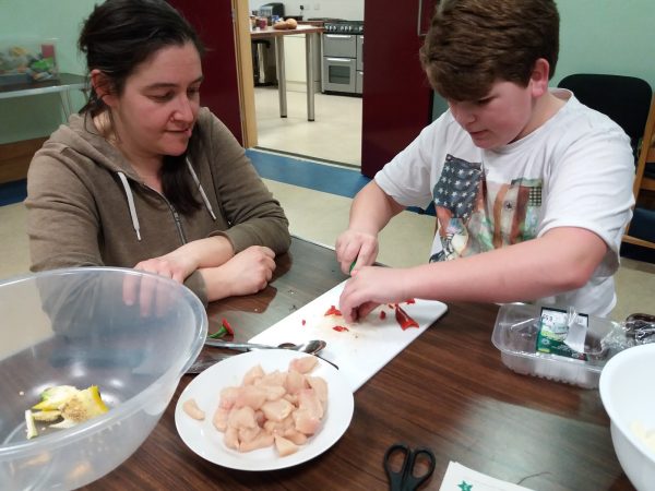 Child learning to cook with member of Food Partnership staff