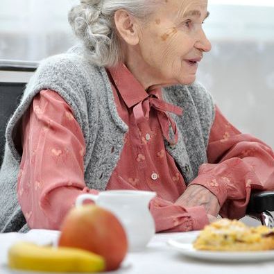 older woman sitting at a table with food