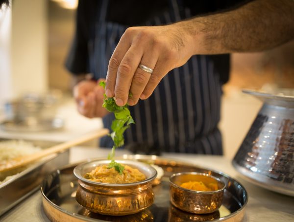 hand sprinkling herbs onto curry
