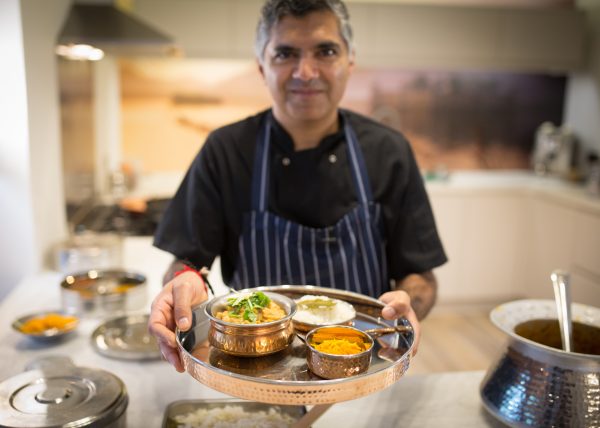 Minesh Indian chef holding bowls of food