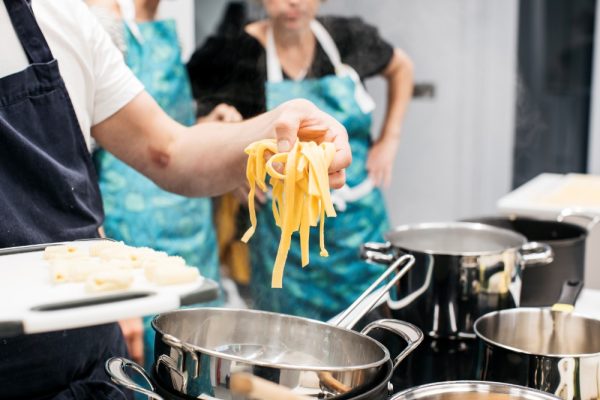 hand holding pasta over pot of boiling water