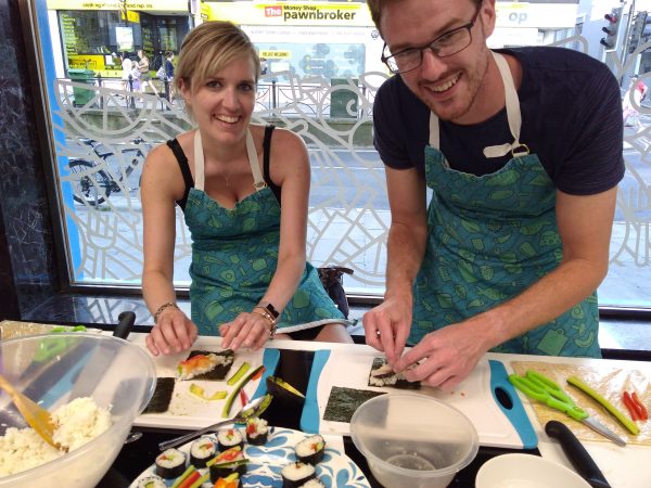 smiling couple rolling sushi