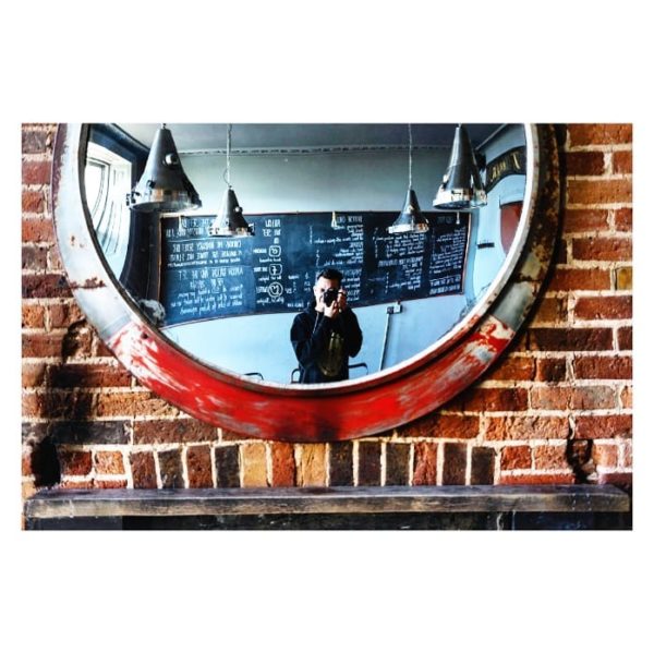 man with camera looking in the mirror