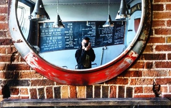 man with camera looking in the mirror