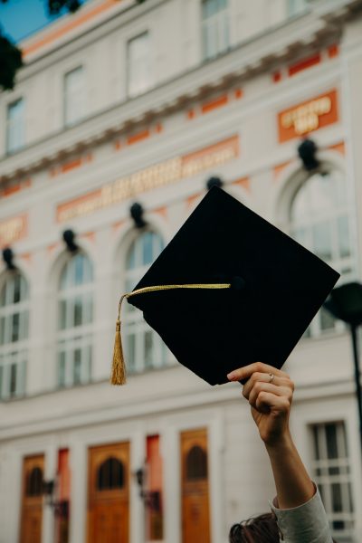 A hand thrusting a graduation cap in the air.
