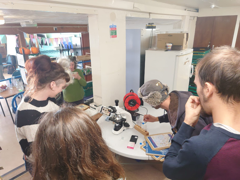 Tom from Old Tree Soil, who helped install the compost tumblers, is showing participants through a microscope at compost sample from the first tumbler to see how living it is, we found nemotodes in this sample! 