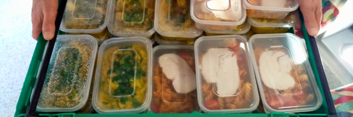 A volunteer carries a tray full of pre-packed home cooked meals, ready to go out for delivery to households who were vulnerable or shielding. 